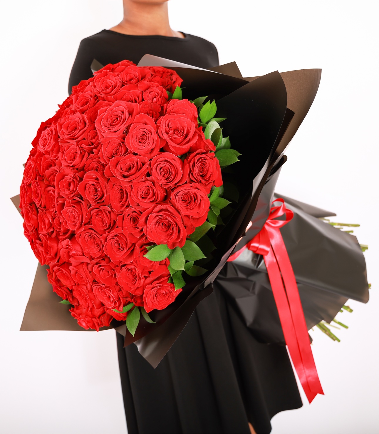 Dome bouquet of red roses wrapped in black, held for scale